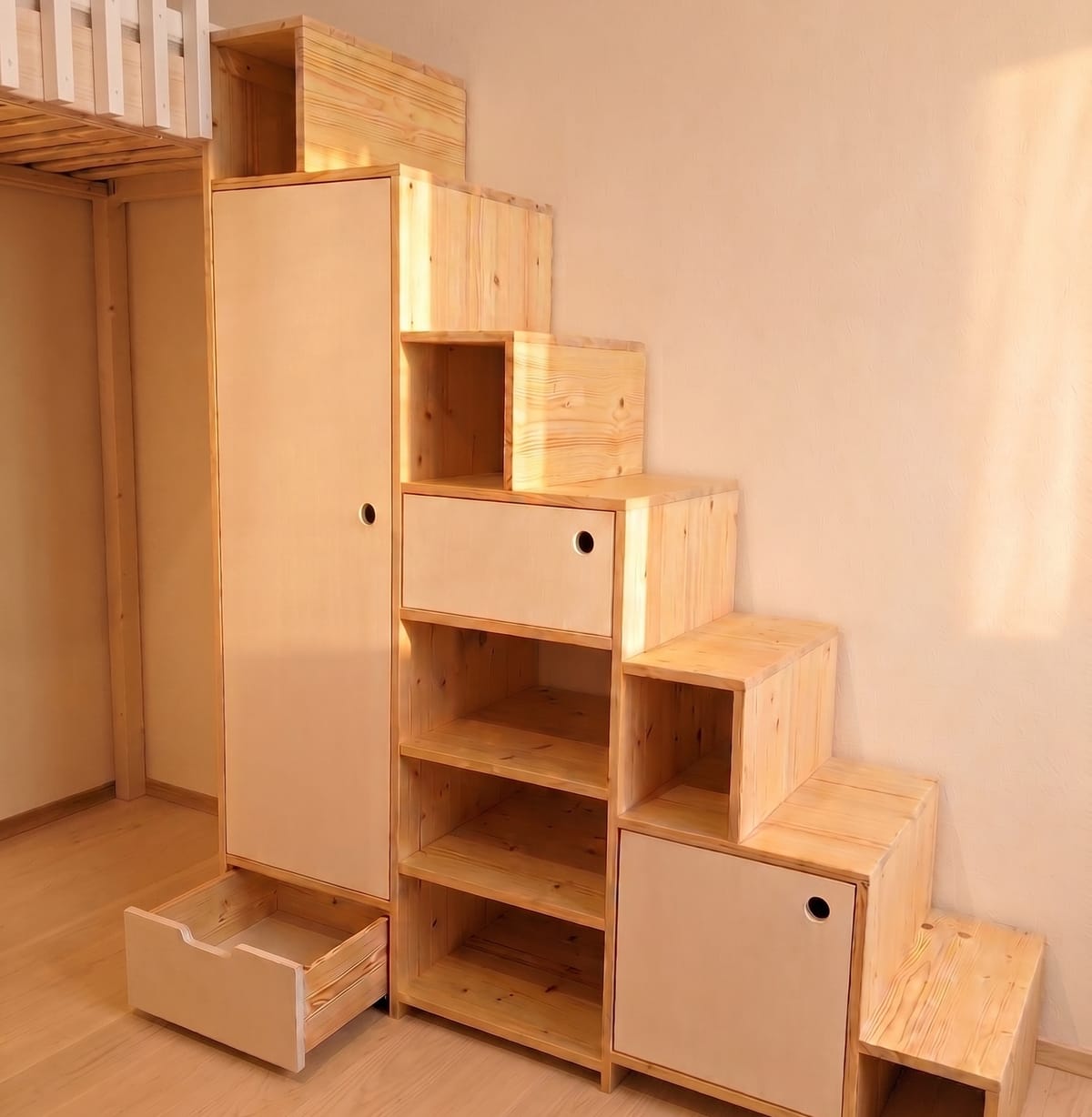 Maßgefertigte Hochbett-Treppe aus hellem Holz mit eingebauten Regalen, Schubladen und Schranktüren als Stauraum