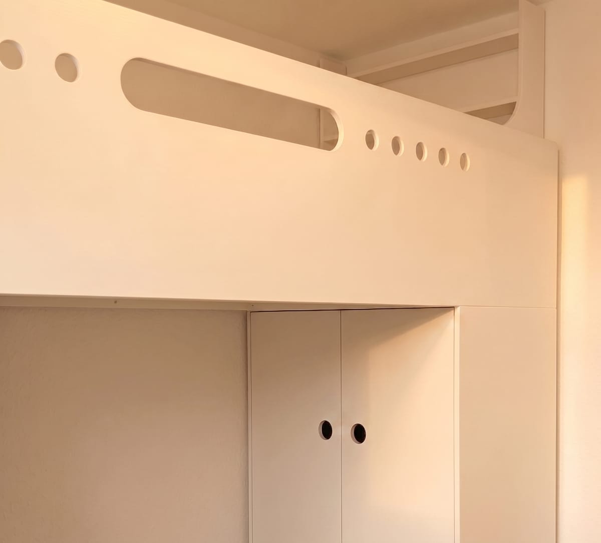 Weiß lackiertes Kinderhochbett nach Maß mit runden Grifflöchern und eingebautem Kleiderschrank darunter